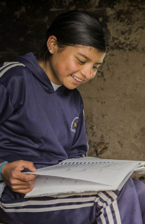 Three girls doing their homework in the light of a solar powered lamp